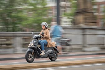 Beeld: vrouw op scooter in Amsterdam